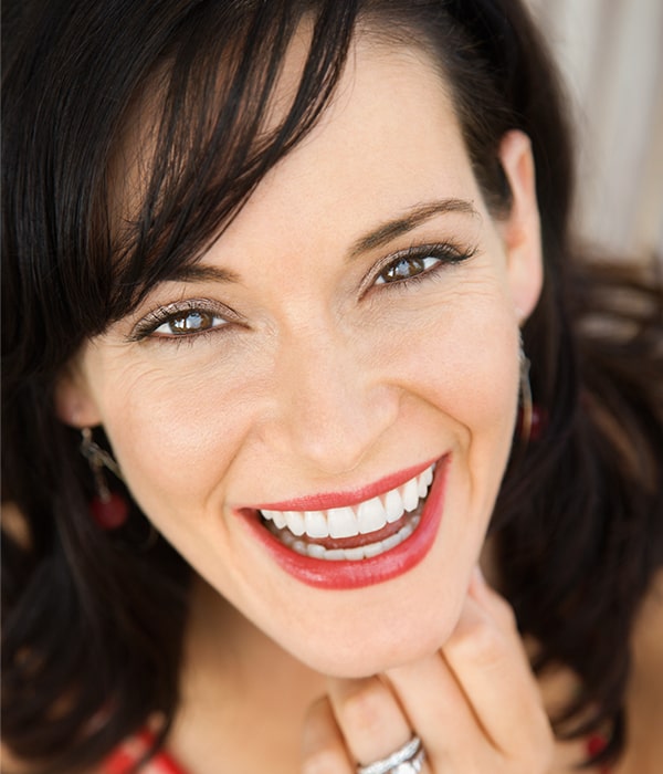 Woman smiling and leaning on chin.