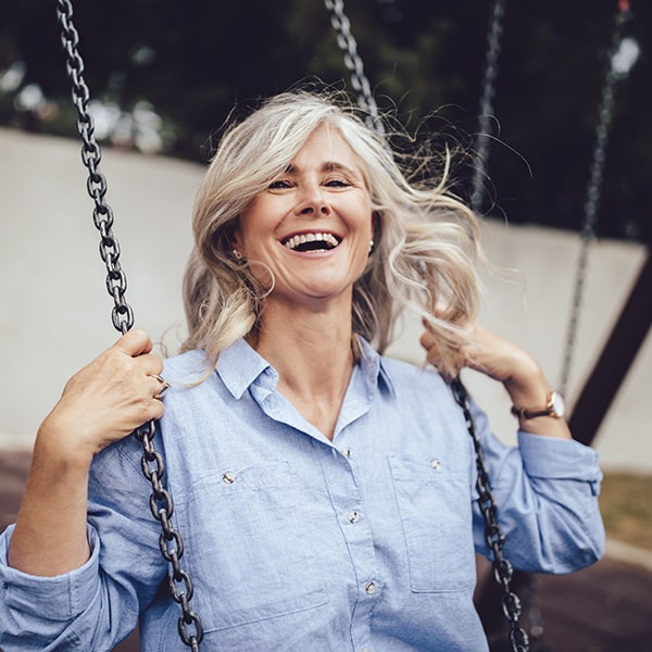 A mature woman swinging while smiling